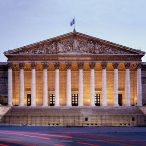The Assemblée Nationale in Paris illuminated at dusk, a popular destination for travelers booking New York to Paris business class flights.