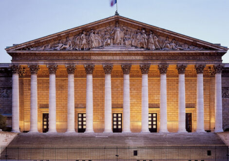 The Assemblée Nationale in Paris illuminated at dusk, a popular destination for travelers booking New York to Paris business class flights.