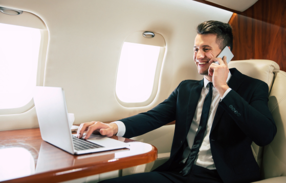 Business traveler on business class flights using laptop and phone